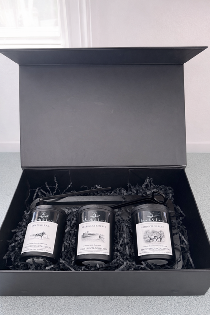 Three candles in a black gift box with white labels.