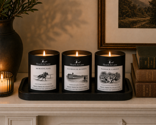 Three candles with labels on a tray on a decorative shelf.